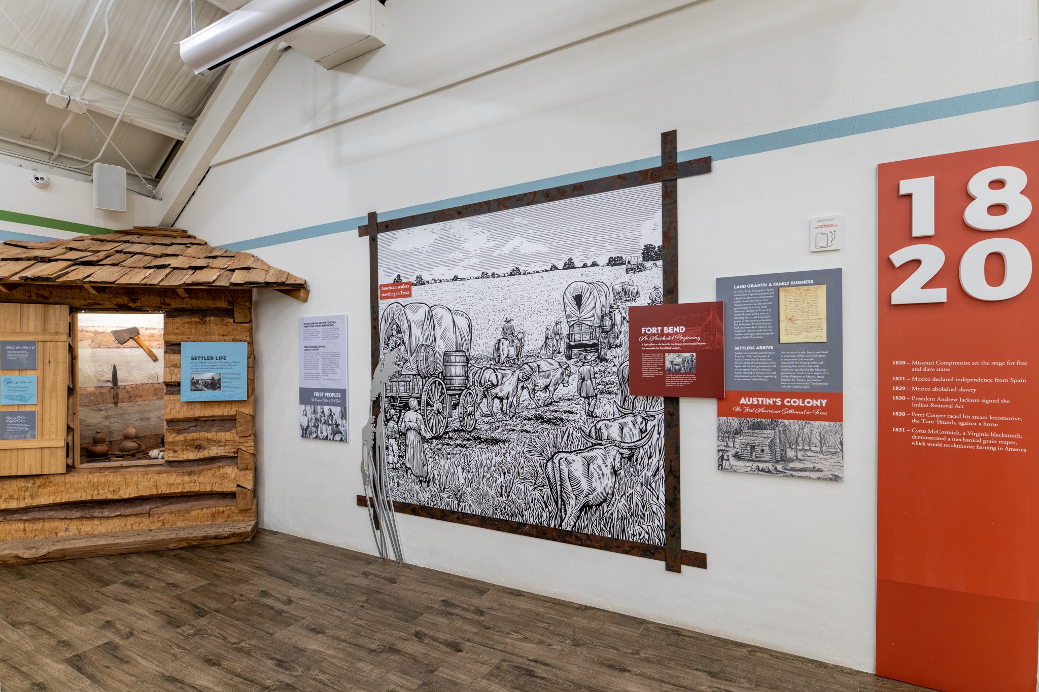 A museum exhibit features a log cabin section, historical panels, and a large black-and-white mural of settlers with covered wagons. A red panel on the right displays the year "1820" with related historical information.